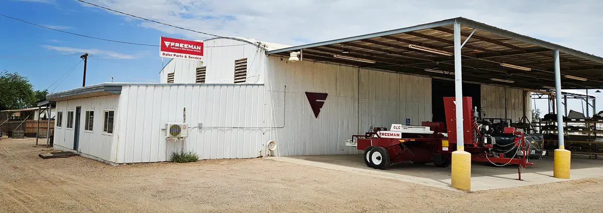 Exterior of Freeman store in Holtville with a side-feed baler sitting outside.