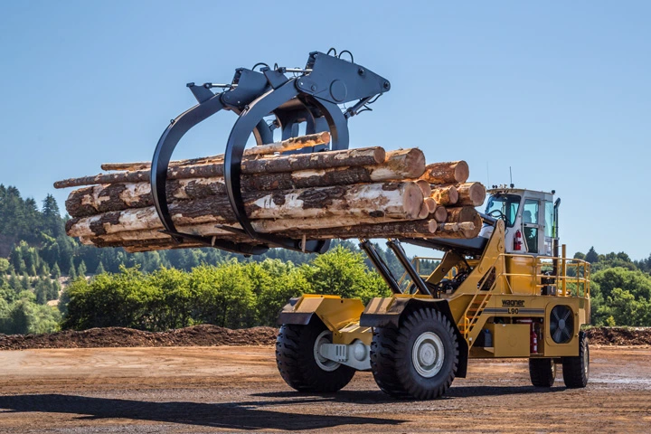 Yellow 2WD Wagner Logstacker driving with a raised load of logs